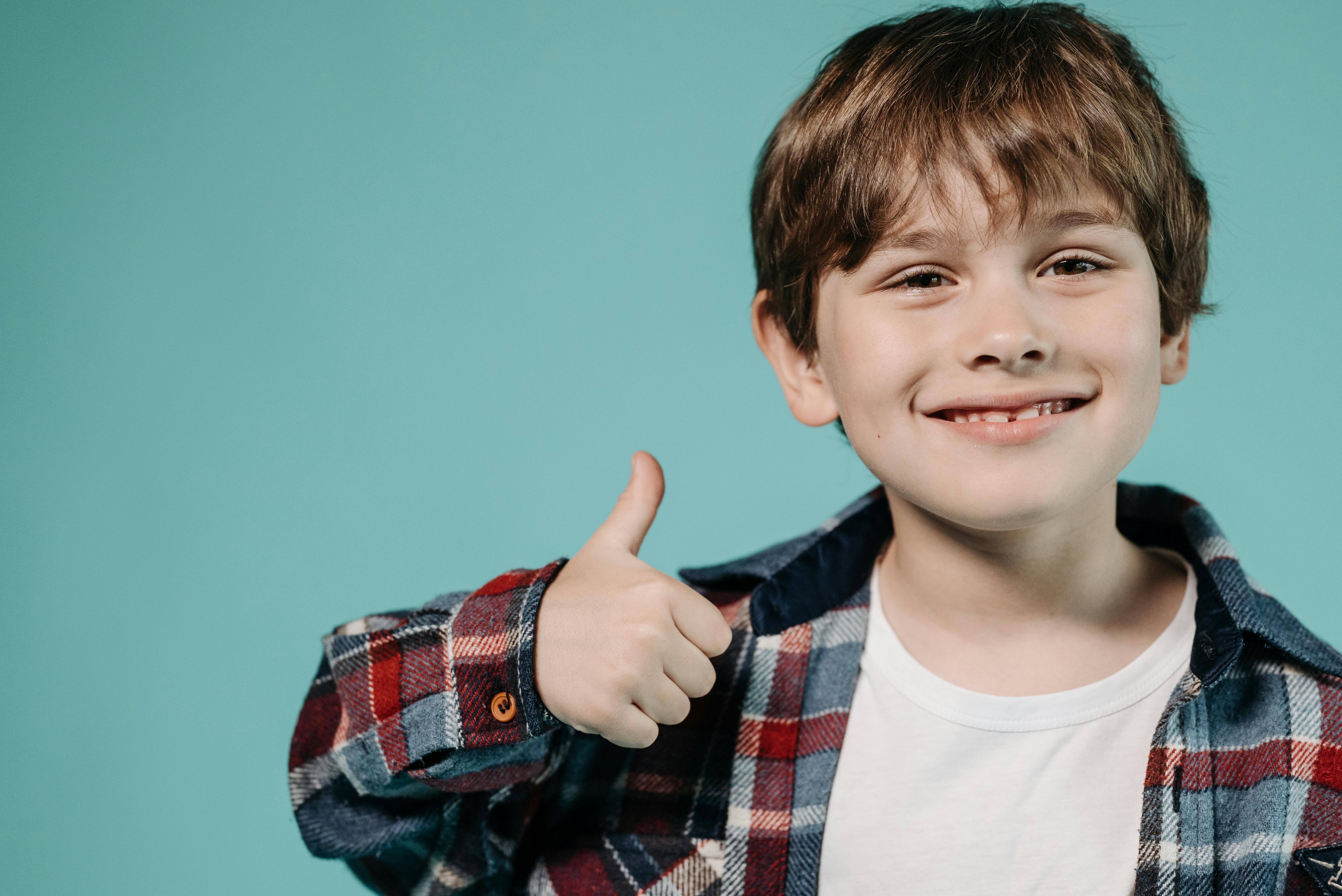 Dečak pokazuje lajk prstom. Srećan i nasmejan dečko pokazuje znak 'okej'. Samopouzdanje kod dece.